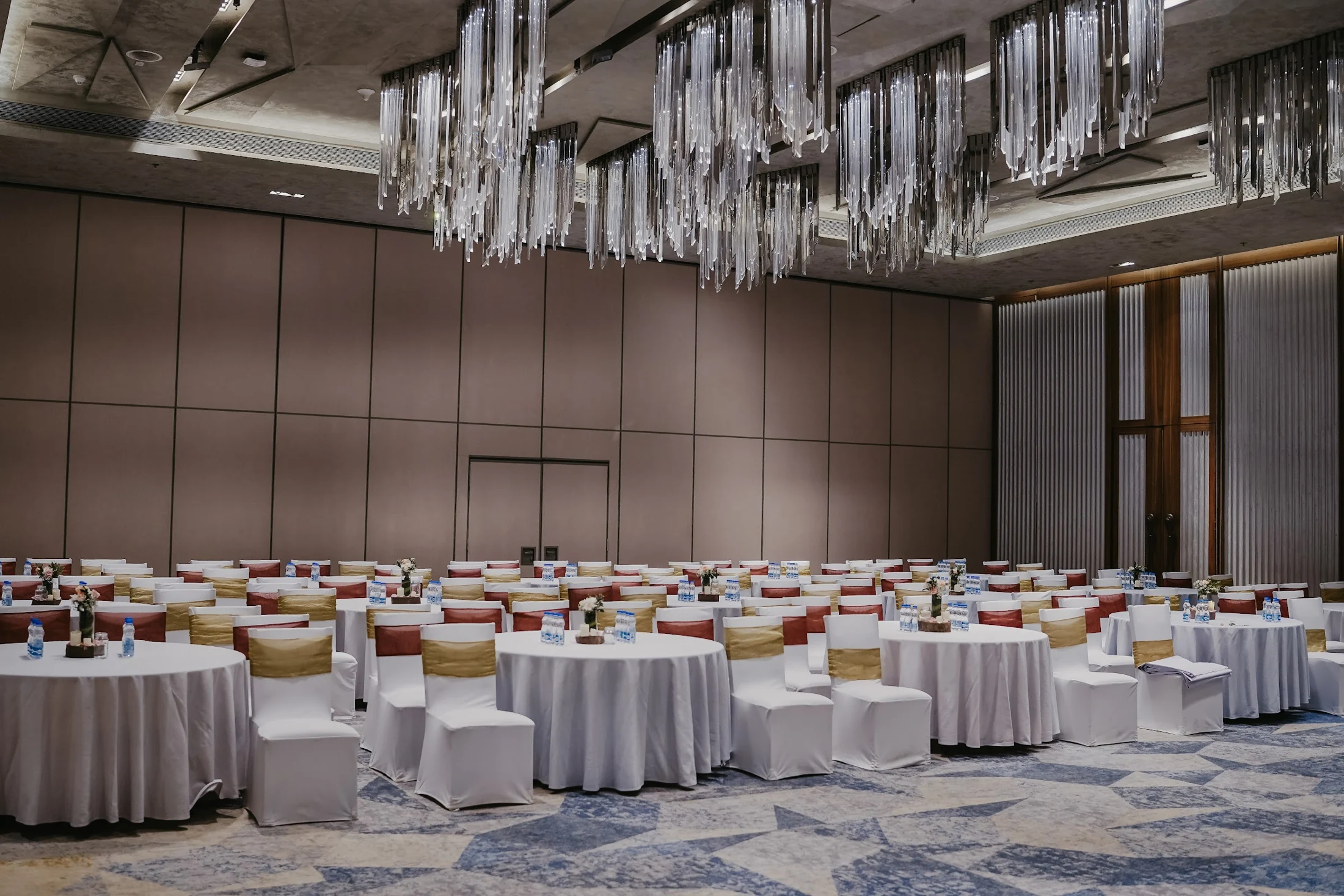 Round guest tables and white chairs arranged in an indoor banquet space