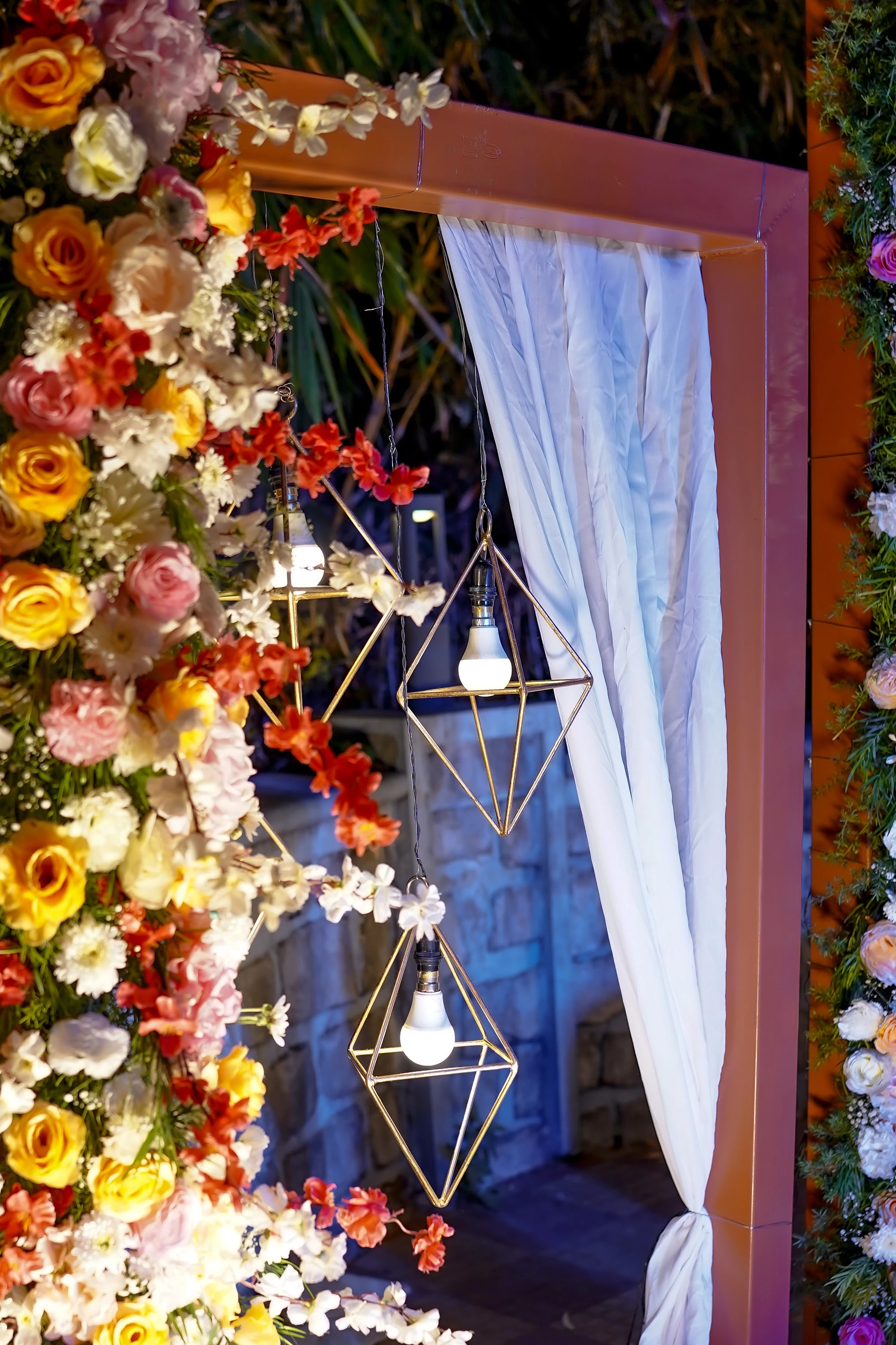 Flowers, drapes and geometric lights framing an evening celebration