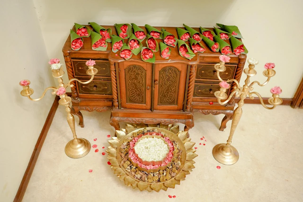 A carved wooden heritage display styled with brass lamps and a floral arrangement