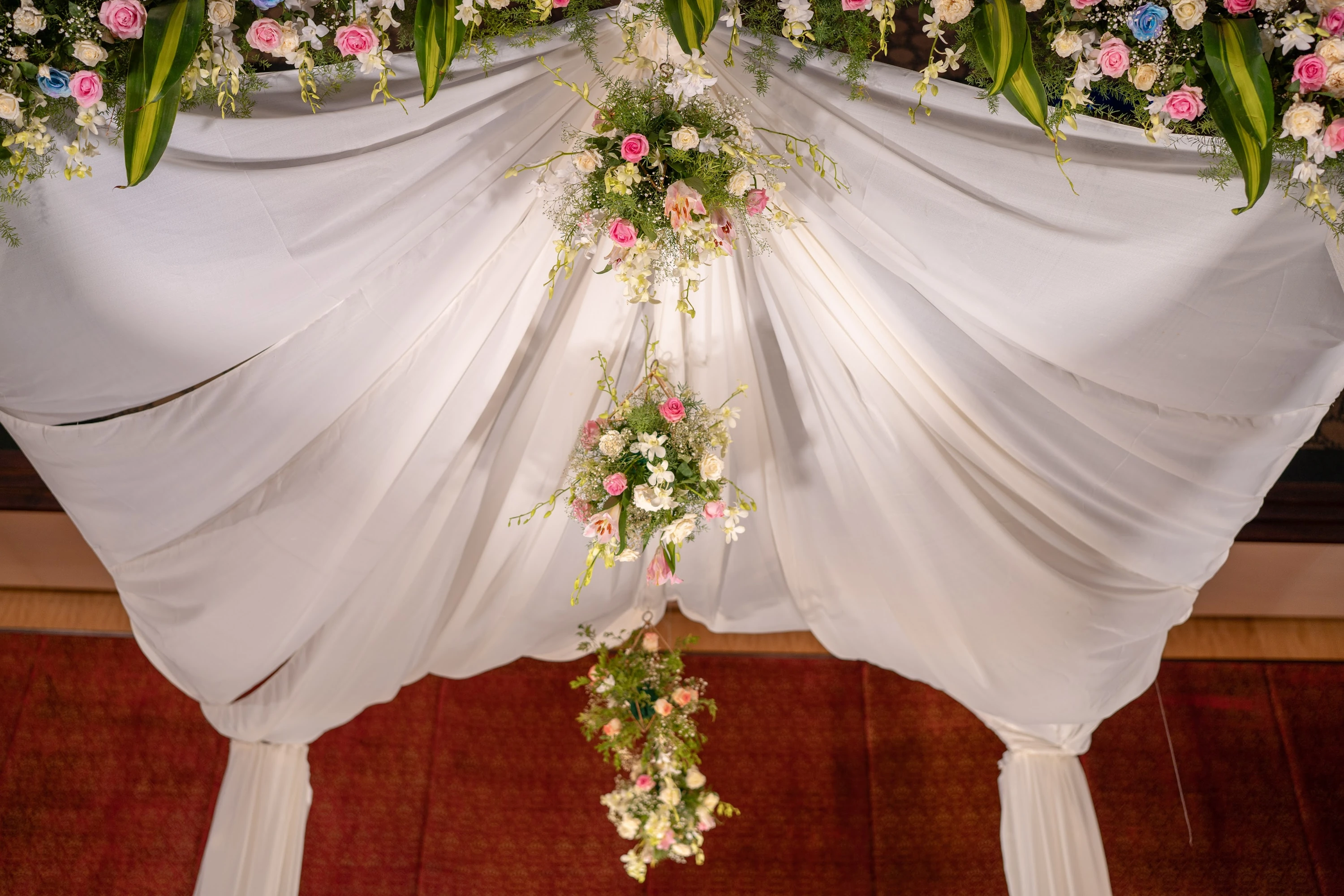 The draped canopy and flowers above a compact indoor mandap