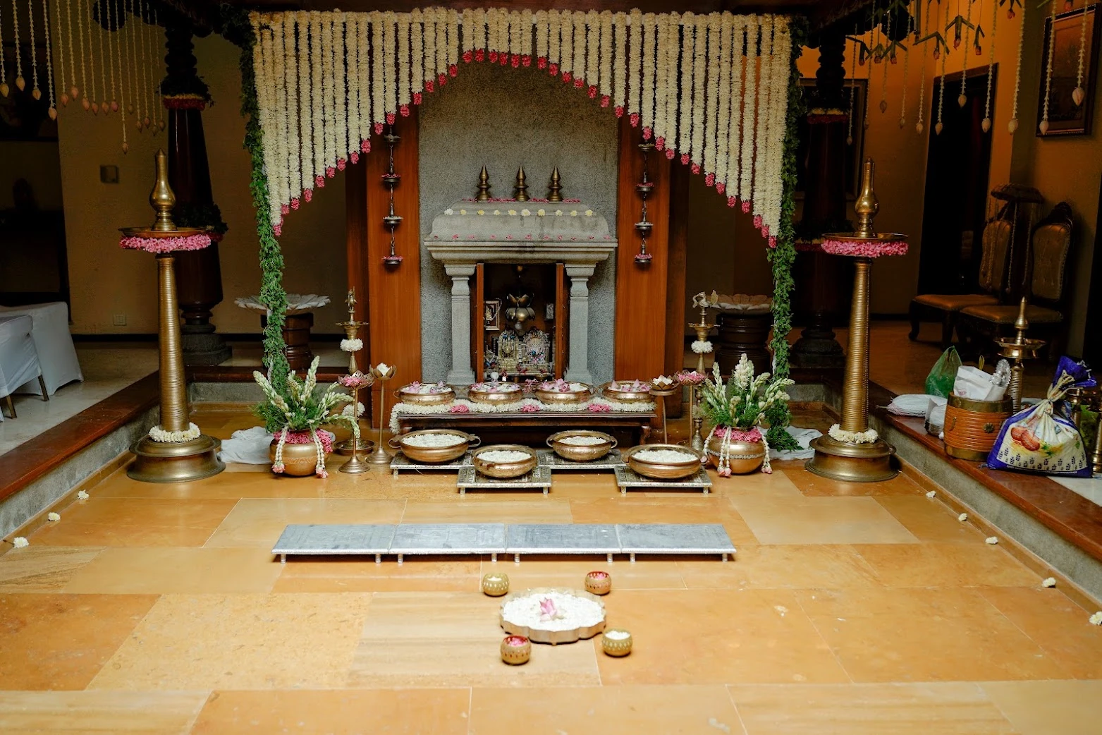 Traditional ceremony setting with white flower garlands, brass lamps and ritual vessels
