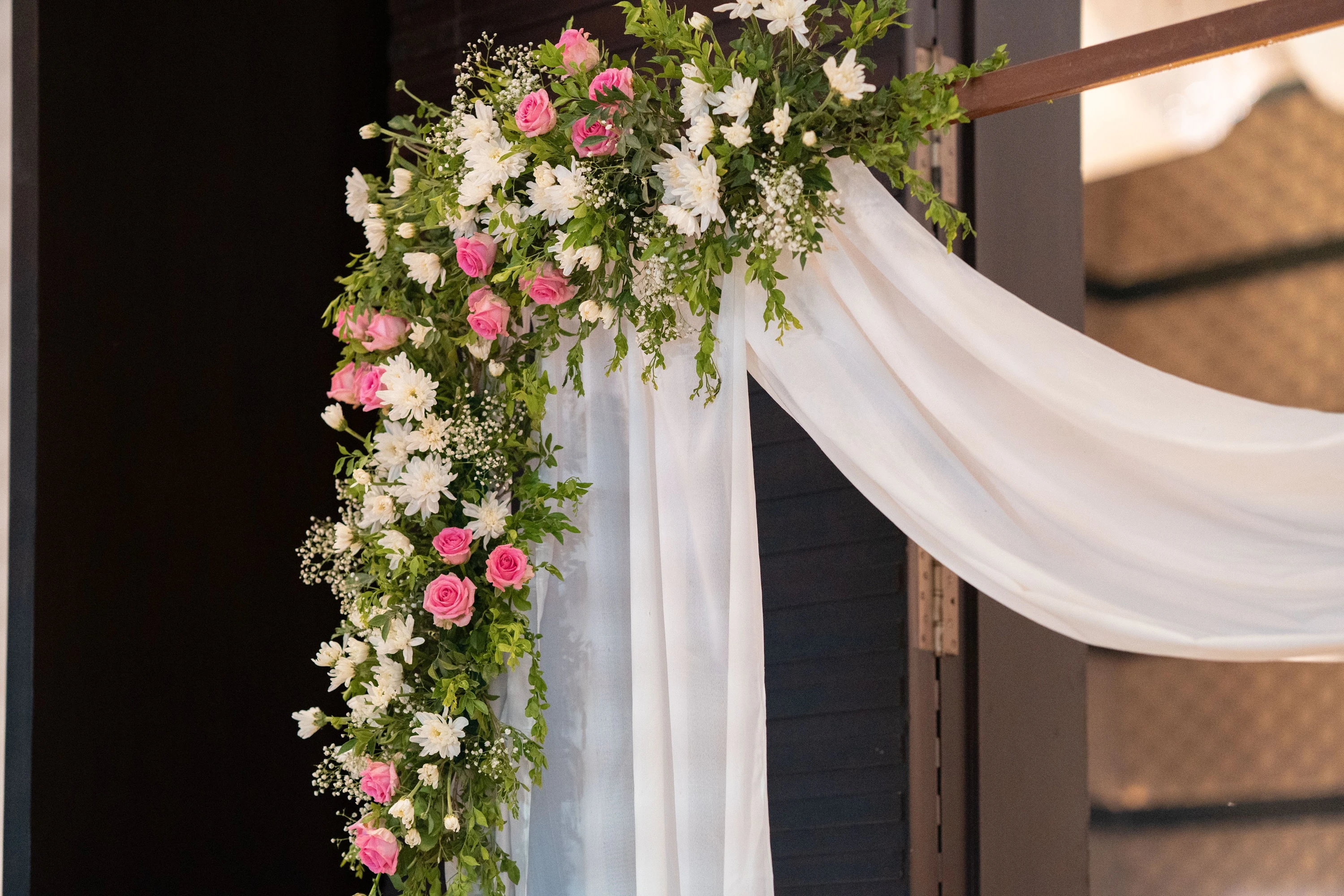 Pink and white flowers framing a softly draped ceremony pillar.