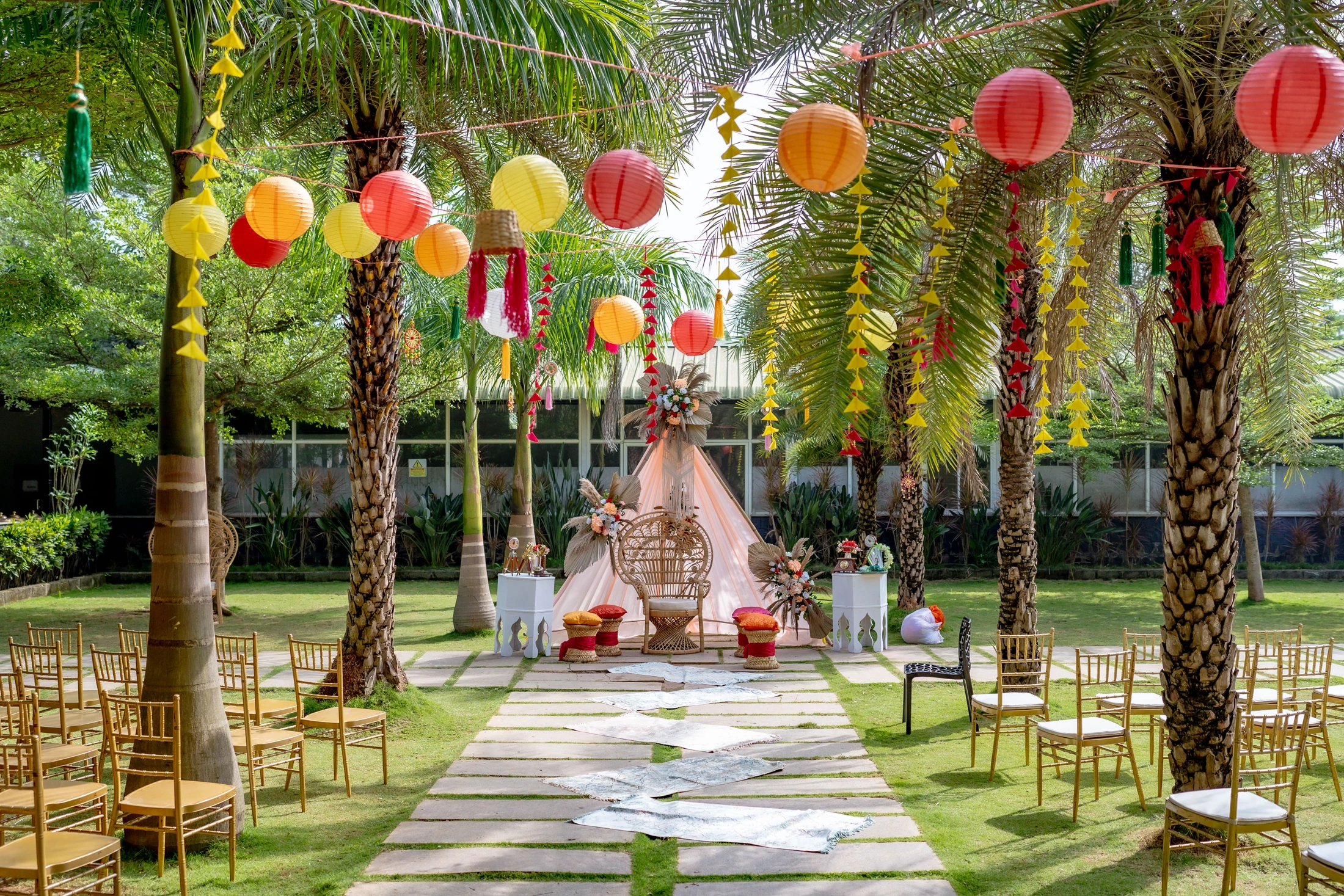 Outdoor celebration seating with gold chairs, a central aisle and colourful lanterns