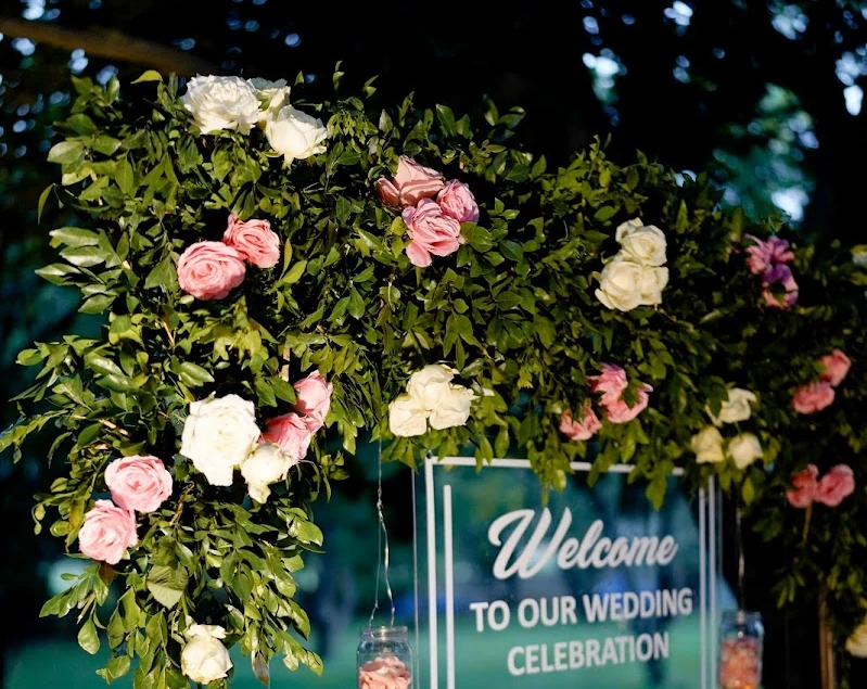 Pink and white flowers framing a welcome message with hanging candle jars
