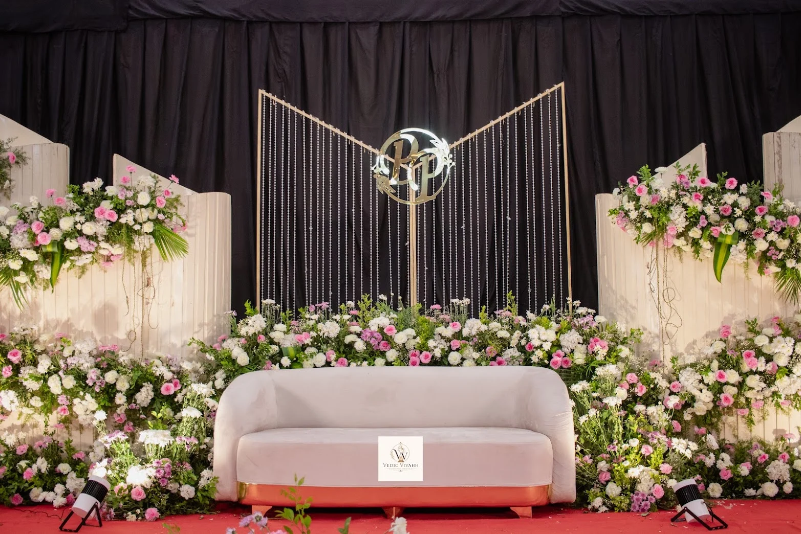 A pale sofa and geometric frame contrast with the dark draped backdrop.