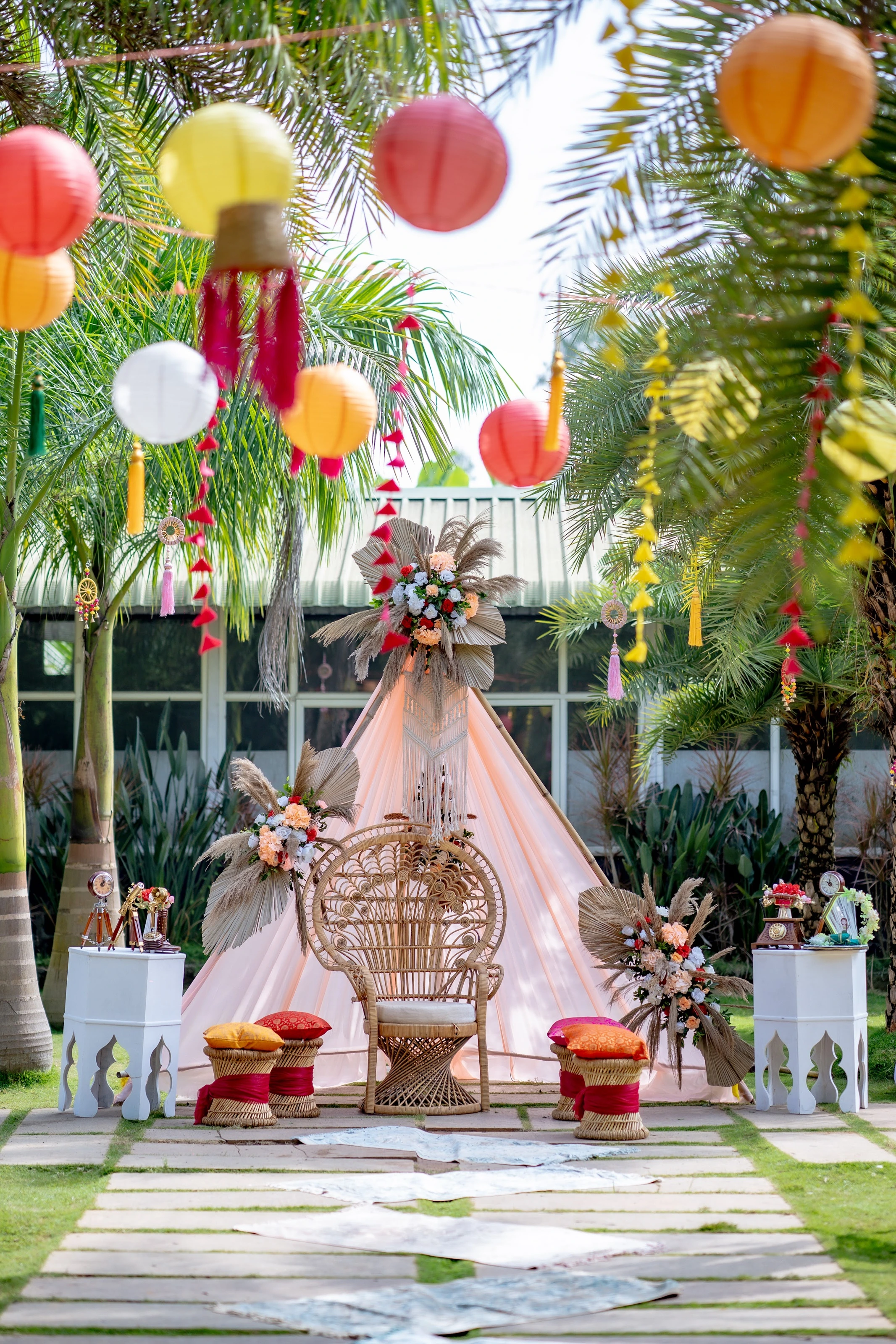 Colourful suspended lanterns and bright drapes above a garden celebration setting