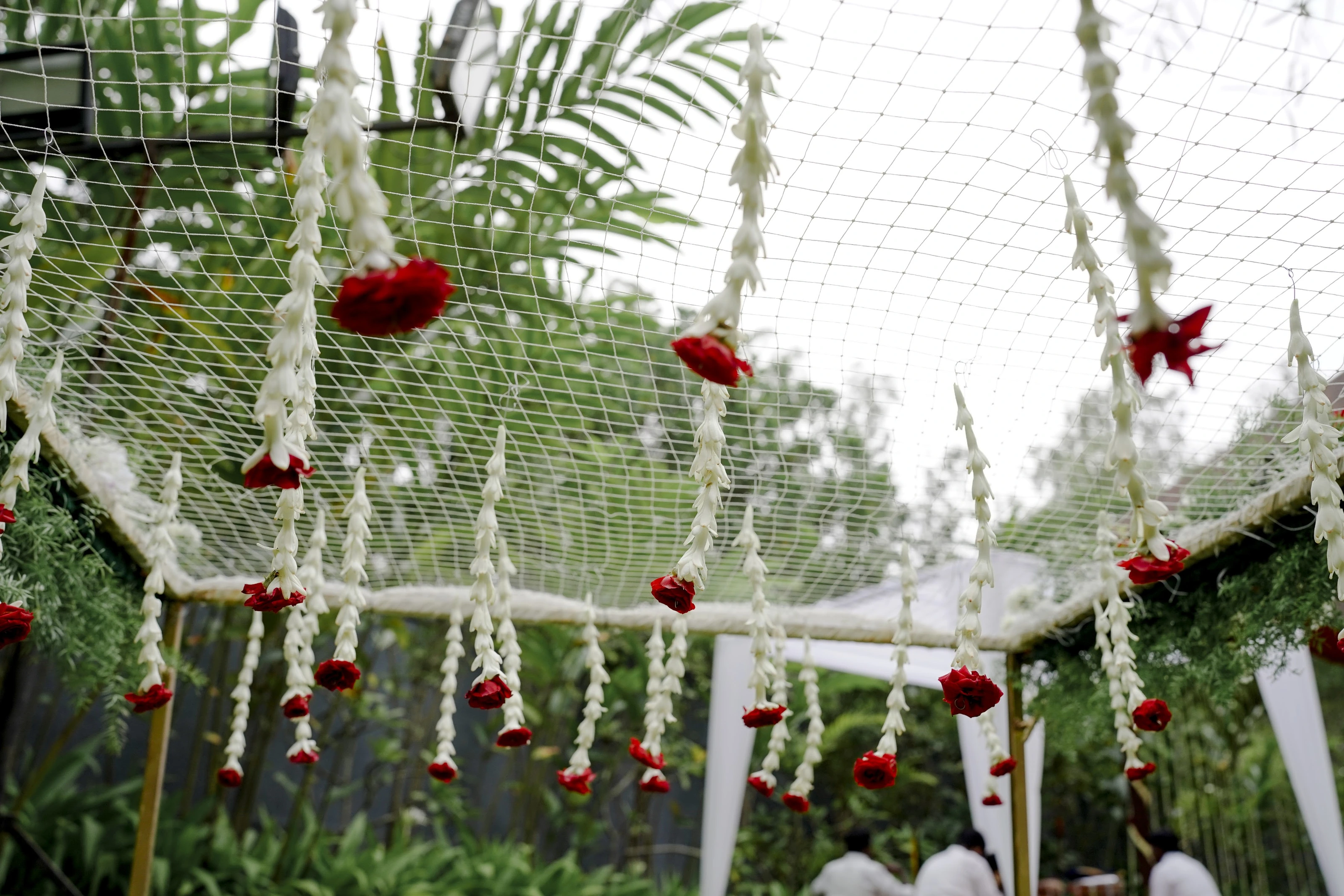 Hanging flower garlands around a ceremony canopy against green palms