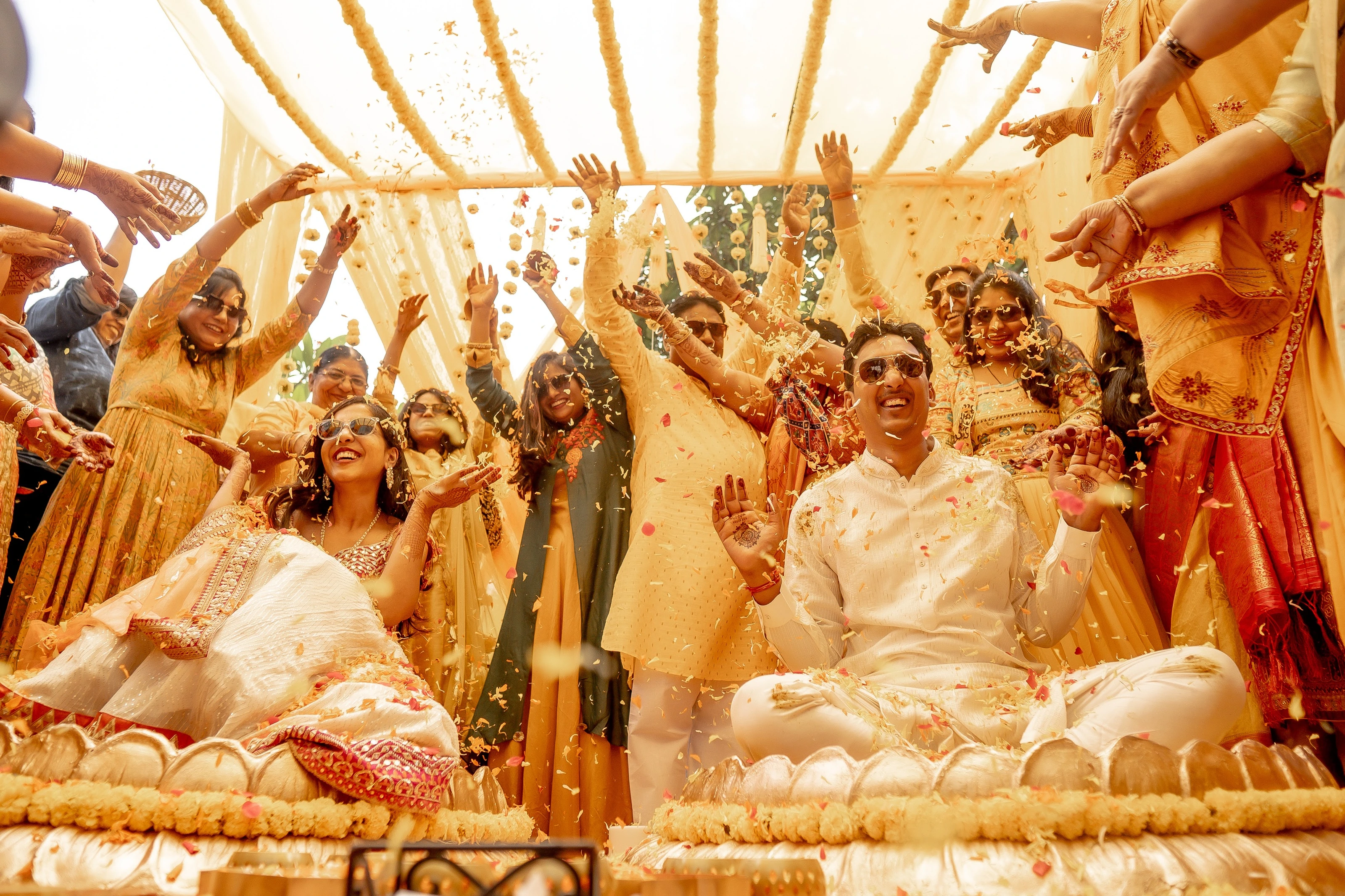 A garden haldi setting with yellow drapes, floral seats and flower-petal baskets