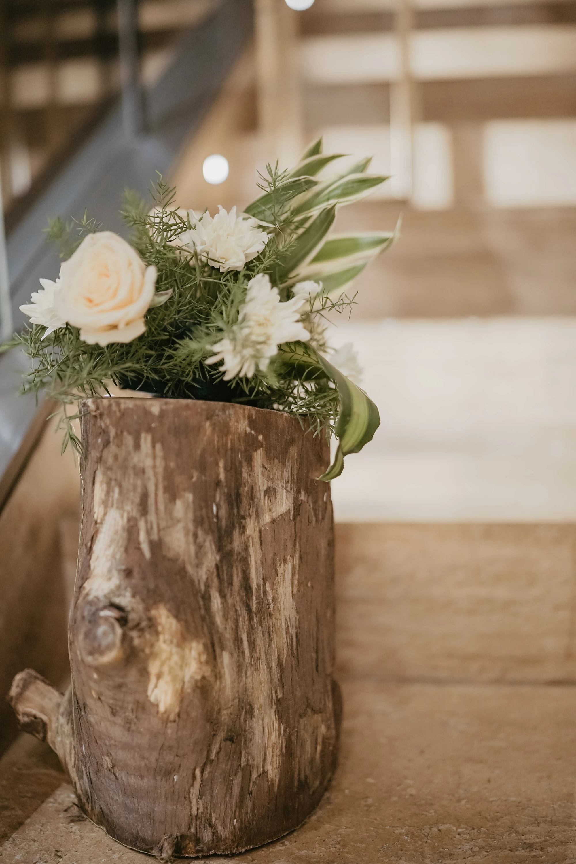 A floral welcome detail in a tall vase beside the venue staircase
